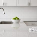 A clean kitchen countertop with a bowl of green apples and a folded towel.